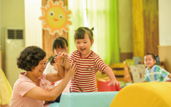 近年來(lái)，各地著力解決3歲以下嬰幼兒家庭入托難、入托貴等 問題，大力發(fā)展完善普惠托育服務(wù)體系，不斷增強(qiáng)人民群眾對(duì)普惠 托育服務(wù)的獲得感和滿意度，促進(jìn)嬰幼兒健康成長(zhǎng)。圖為2024年 9月4日，江西省奉新縣示范幼兒園托育班的老師和孩子們?cè)诳鞓?地玩耍。